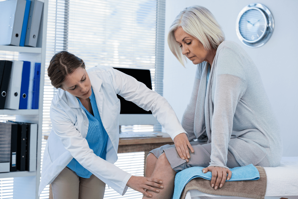 The doctor examines a patient with arthrosis of the knee joint